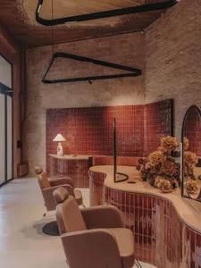 A modern salon interior featuring sleek, red ceramic tiles and elegant seating.
