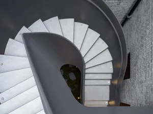 Modern staircase designed in grey concrete with a spiral slide.