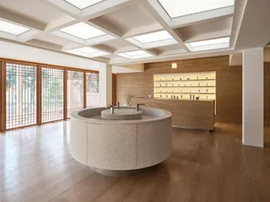 Modern spa interior featuring a circular granite counter and a wooden shelf with illuminated bottles.