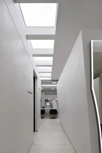 A bright, white corridor interior with skylights and concrete walls.