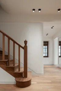 Modern interior featuring wooden stairs with wooden railings and flooring, white walls, and recessed lighting.