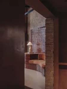 A cozy living room with curved brick tiles, a comfortable bench, and minimalist decor.