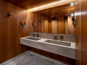 Modern industrial bathroom with concrete walls and countertops, featuring large mirrors and minimalist design.