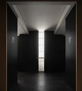 A minimalist commercial hallway with black panels and a high ceiling.