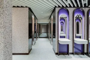 A minimalist commercial interior with concrete walls, a white floor, and purple lights.