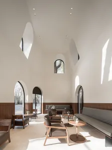 A spacious, modern coffee shop interior with wooden furniture and high ceilings.