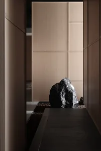 A modern corridor with a large boulder and concrete floor.