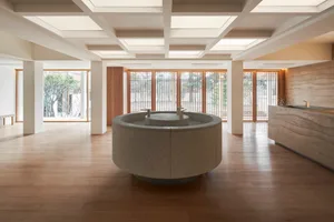 Modern hotel lobby with natural stone flooring and a circular central feature.