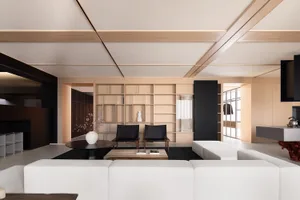Modern minimalist living room with white couch, black chairs, and wooden shelves.