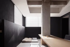 A contemporary living room designed with minimalist aesthetics, featuring concrete and wooden elements.