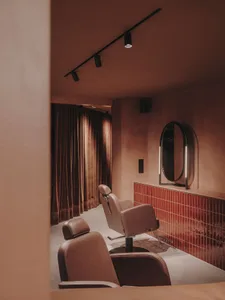 Modern minimalist salon with brown leather chairs, tiled flooring, and a sleek design aesthetic.