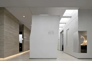 An interior shot of a modern nursing room with white concrete walls and a white column.