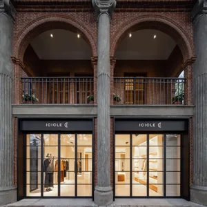 A modern retail storefront with a red brick exterior, glass windows, and interior lighting.