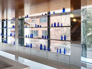 Modern storefront with glass walls and blue bottles displayed.
