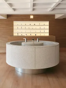 Modern retail storefront featuring a circular granite countertop with two faucets in a minimalist space.