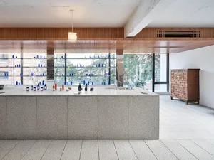 A modern retail storefront featuring a marble counter with bottles and vials displayed on shelves.