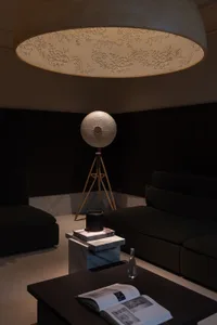 A modern living room with a marble coffee table, black furniture, and unique lighting fixtures.