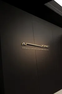 Interior shot of a minimalist corporate office entrance with a metal logo sign.