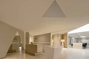A modern office lobby with a wooden reception desk and geometric wall designs.