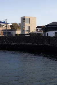 一棟現代磚造水岸住宅，擁有塔狀結構與大面窗戶。