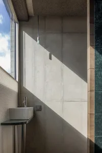 A modern bathroom featuring concrete walls and glass elements.
