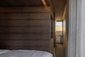 A minimalist bedroom with wooden panels on the wall and ceiling.