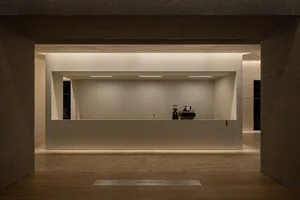 A minimalist coffee shop with a concrete counter, minimal furniture, and soft lighting.