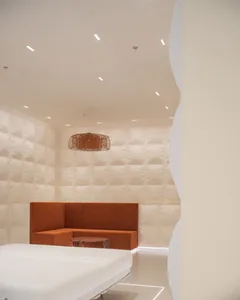 A minimalist interior space featuring a plush, white fabric seating area and a round wooden side table.