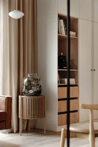 Modern minimalist living room with concrete and wood storage unit featuring built-in bookshelves and a decorative glass terra