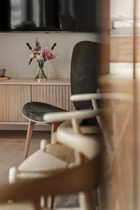 Minimalist living room with wooden furniture and a vase of flowers.
