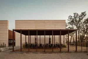 A modern cafe with metal tables and chairs, wooden flooring, and concrete walls and pillars.