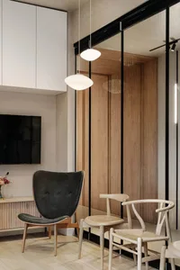 A modern living room featuring a black tufted chair, wooden flooring, and contemporary furniture.