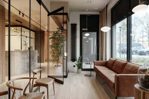Modern living room with a marble floor and wooden furniture, featuring a brown leather sofa and potted plants.