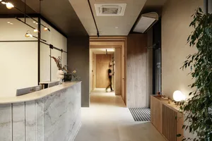 A modern office reception area with a white marble counter, wooden surfaces, and concrete flooring.