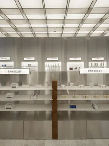 Empty shelves in a modern pharmacy interior with metallic walls and signage.