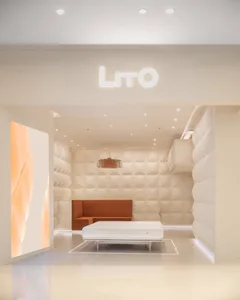 Modern retail storefront with a light, minimalist interior design featuring a white couch and a bed with a bedside table.