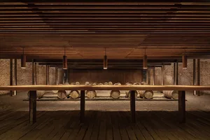 A spacious wine cellar with wooden barrels and a long wooden table.