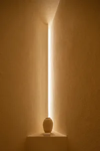 極簡室內空間，一個陶土花瓶被角落射出的窄光束照亮
