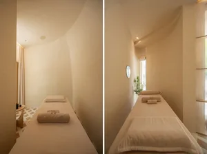 A minimalist spa room with soft-touch materials features a long massage table.