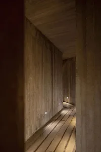 A modern corridor lined with concrete walls and illuminated by recessed lights.