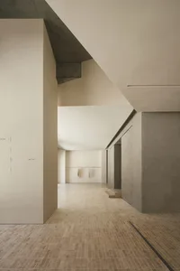 A modern interior space featuring concrete walls and travertine tile flooring.