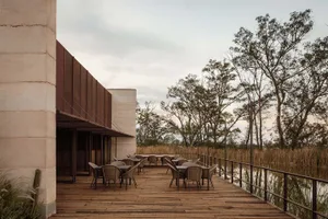 Outdoor seating area of a modern restaurant with wooden tables and metal railings.