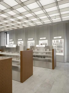 A modern retail store with a sleek, metal pharmacy counter displaying various products.