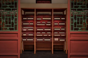 Well-lit retail store interior featuring modern wooden shelves stocked with bottles of products and glass display cases.