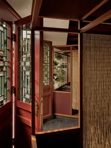 Traditional wooden framed entrance hall interior with bamboo curtain and greenery.