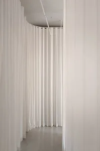 A minimalist installation featuring hanging white fabric panels.