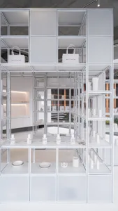 A minimalist retail store with white interior design, featuring shelves and displays of white products.