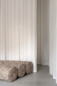 Modern interior design featuring curtains, concrete furniture, and a minimalist aesthetic.