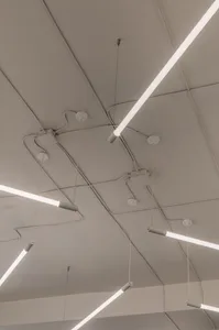 Long modern metallic ceiling lights mounted on white square tiles ceiling