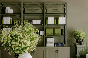 A display of green metal shelves arranged with various products and floral decor in a retail space.